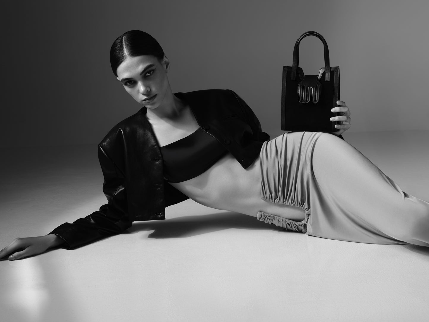 Model holding a handbag against a neutral background