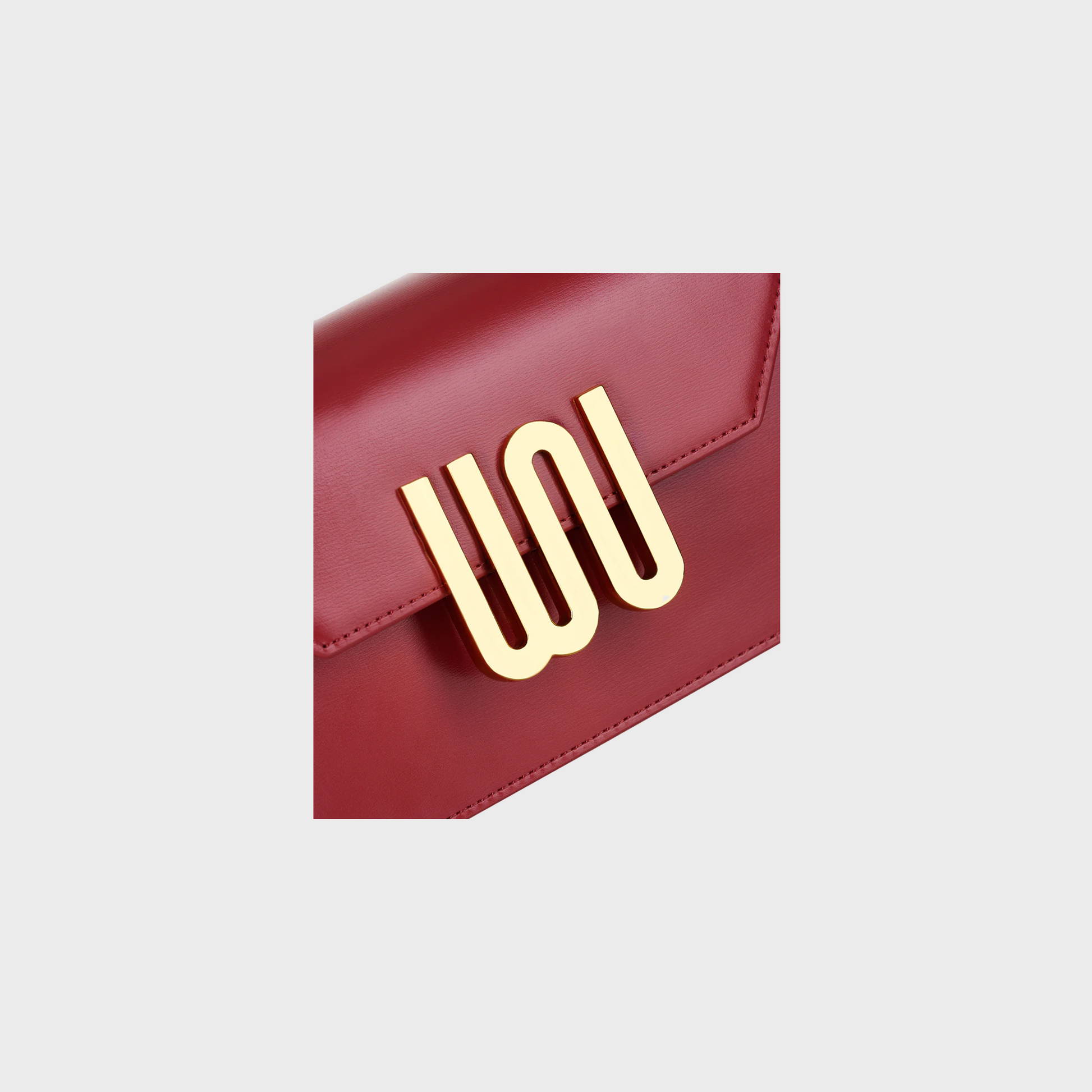Red handbag with a gold logo on a light gray background
