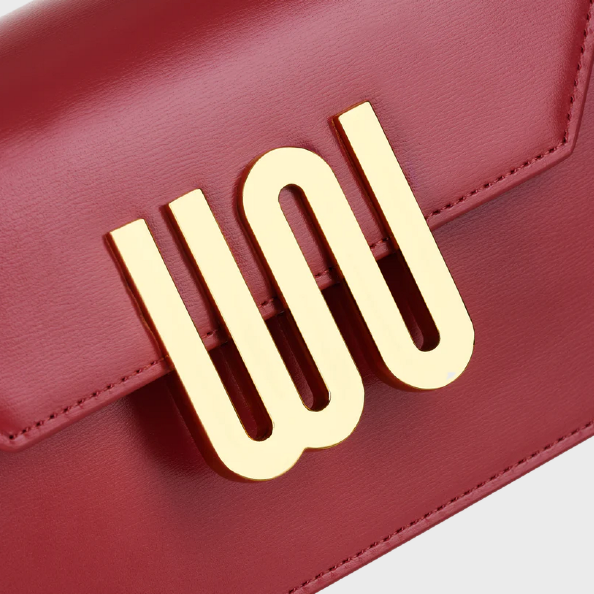 Red handbag with a gold logo on a light gray background