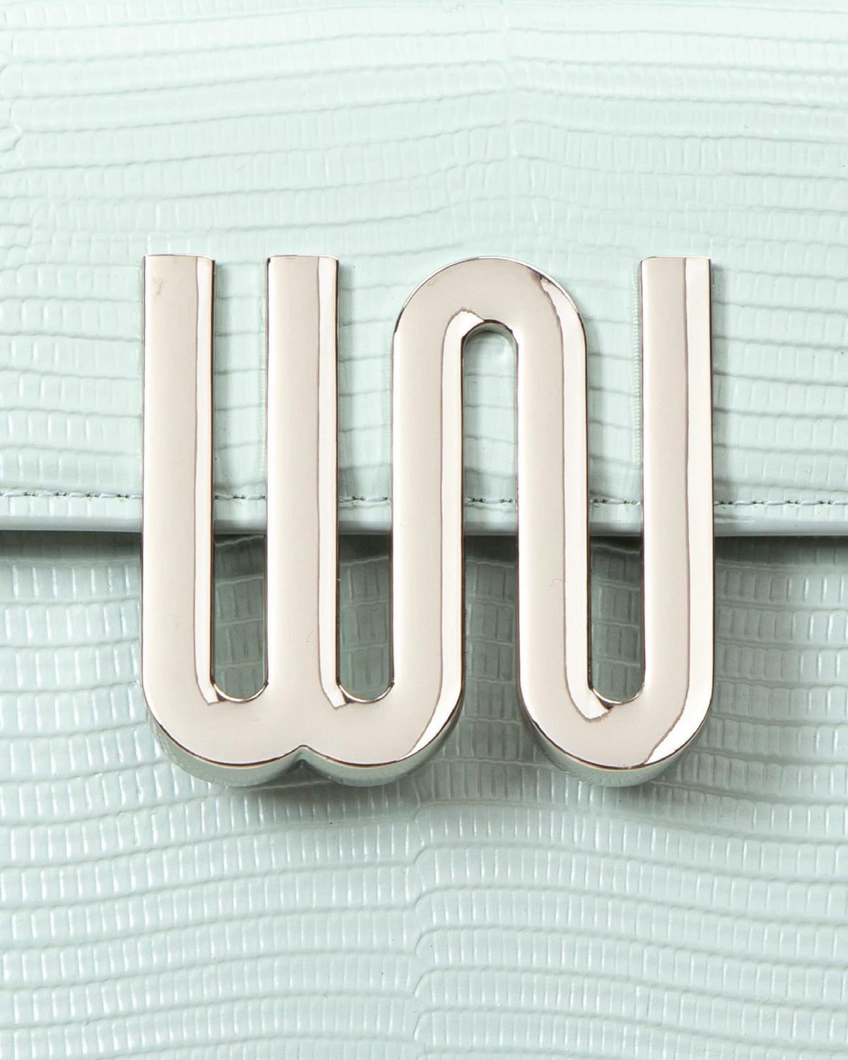 White Noise The Label Bronzite Lagoon, gunmetal WN logo hardware close-up on lizard-embossed leather