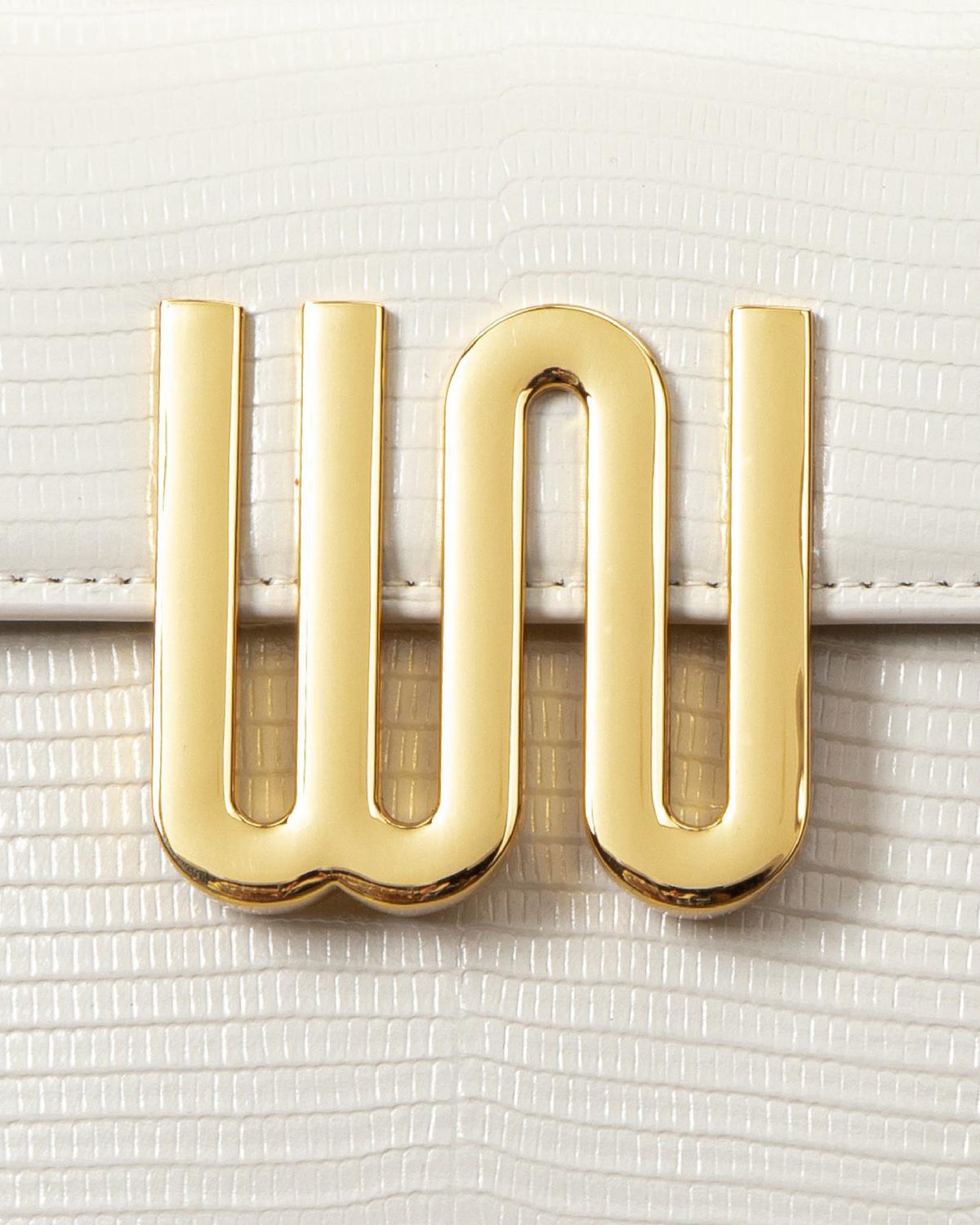 White Noise The Label Bronzite Nougat, gold WN logo hardware close-up on lizard-embossed leather