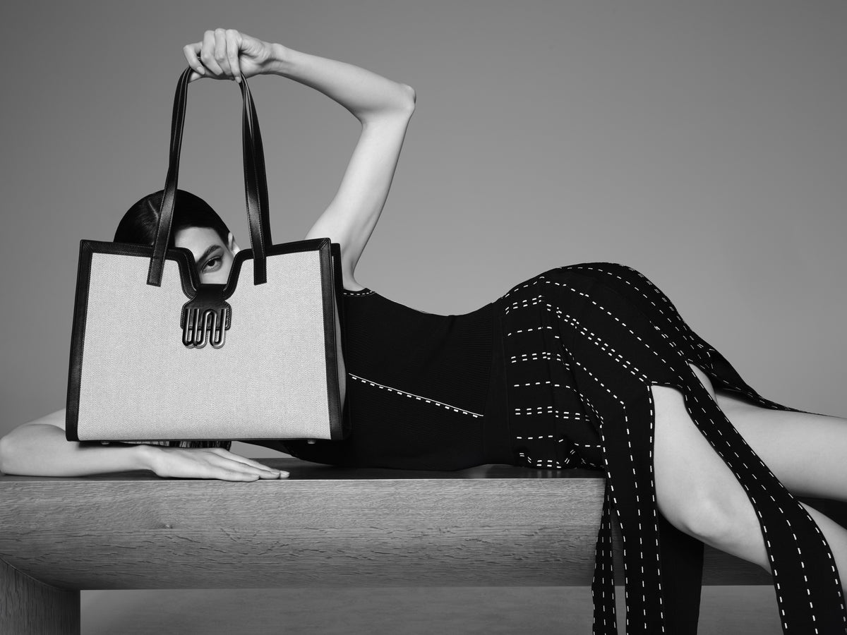 White Noise The Label editorial portrait in black and white: a model lies back holding a tote above her